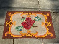 Full view of the rectangular hooked rug showing the floral design and colors.