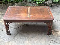 Front view of walnut coffee table with leather top showing visible wear, missing and loose corner trim on the tabletop.