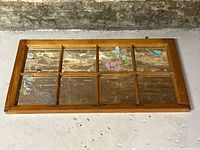 Full view of the antique pine wooden window frame mirror showing six glass panes and visible floral vinyl stickers on some panes, placed on a concrete surface with brick background.