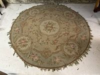 Full view of round antique Aubusson carpet showing floral pattern and overall condition including fringes