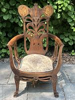 Front view of the ornate Victorian armchair showing carved wood details and floral tapestry seat.
