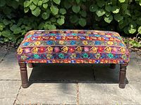 Front view of entire footstool bench showing upholstery pattern and wooden legs