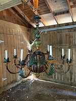 Full view of the large Italian 8-arm chandelier hanging in a barn-like wooden setting. Shows the overall shape, size, and color scheme.