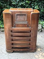 Front view of the antique Marconi wooden console radio showing the dial, knobs, and wooden grille speaker cover with visible surface wear and scratches.
