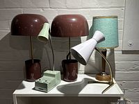 All five lamps displayed together on white surface against brick wall