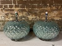 Two turquoise crackle glass lamp bases side by side, showing round, quilted diamond pattern and chrome fixtures