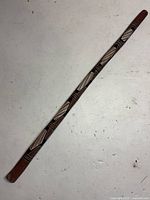 Full view of the vintage painted didgeridoo on a white surface.