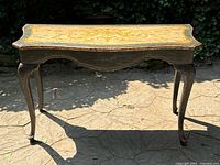 Front view of vintage solid wood console table with ornate hand-painted floral design on top and cabriole legs.