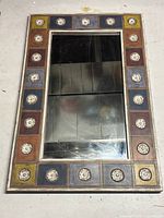 Full view of the rectangular mirror with multicolor wooden patchwork frame and white carved floral motifs around the glass panel.