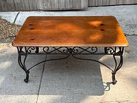 Front view of vintage wrought iron coffee table with pine top showing scratches and overall condition.
