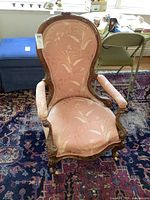 Front angle view of the antique chair showing upholstery and carved wooden frame.