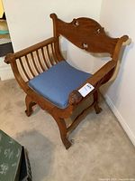 Front-side view of antique wooden armchair showing lion head carved armrests and blue upholstered seat.