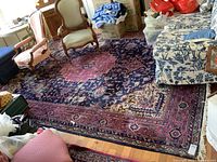 Wide view of entire rug under furniture and boxes showing overall pattern and size