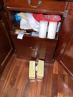 Photo of large drawer with two large white pillar candles and boxed items around