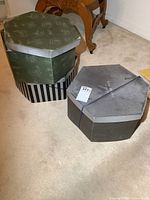 Three hexagonal hat boxes stacked on carpet, two closed and one partially visible green Disney themed box.