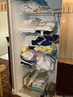 Photo of linen closet shelves with stacked towels, folded bedspreads, and boxes below