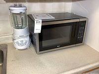 Microwave and blender side by side on countertop.