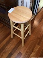 Full view of the round seat stool showing top and legs on wooden floor