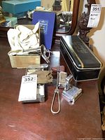 Overview of assortment of old doctor tools including metal boxes, surgical instruments, and a doctor's book on a wooden dresser surface.