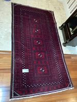 Full view of the red and navy rug laid flat on hardwood and tile floor
