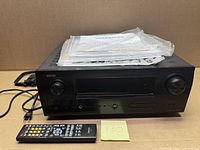 Front of Denon AVR-1610 receiver with remote and manuals displayed