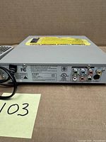 Rear of Coby DVD-224 showing RCA outputs and labels, remote alongside