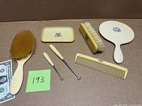 Full set displayed: hairbrush, clothes brush, comb, tray, two manicure tools, dollar bill for scale