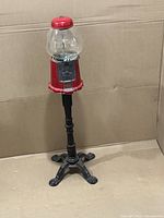 Full view of red gumball machine on tall black cast iron stand
