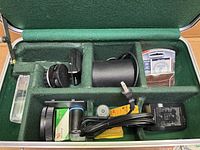 Interior of case with compartments containing flash, charger, film, lens case