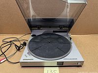 Turntable with lid open showing platter, tonearm and cords