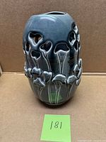 Front view of glazed ceramic vase showing relief floral motif and cut-out design