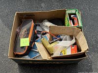 Cardboard box containing beige glue gun, Tekton pouch, Yard Bags box and packaged hardware