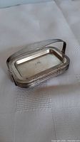 Stack of six small chrome rectangular ashtrays in holder, showing deco banding on edges and curved handle.