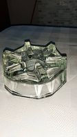Clear crystal ashtray with geometric raised sections, photographed on a light-colored checkered fabric surface