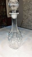 Full view of the moulded glass decanter with stopper, showing its shape and height.