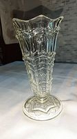 Full view of the clear Depression glass vase showing geometric decorative pattern and flared scalloped rim.