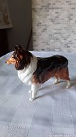 Side view of Royal Doulton sheep dog figurine showing tricolor paint and repaired leg