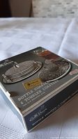 Box front showing set of silverplated bottle and tumbler coasters from brand Colne, unopened.