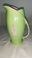 Side view showing green ceramic pitcher with crest design