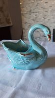 Photo of turquoise ceramic swan planter showing full body and gold accent details on wings and beak.