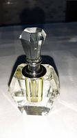 Photo of vintage crystal perfume bottle showing faceted design and stopper with yellow liquid inside.