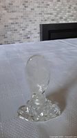 Side view of vintage clear glass perfume bottle showing faceted base and oval stopper