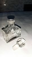 Clear glass vintage perfume bottle with geometric faceted glass stopper detached, showing white stopper base