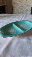 Top angle photo showing full length and divided parts of the turquoise ceramic serving dish with white floral designs.