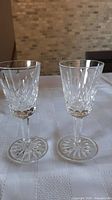 Pair of clear crystal liqueur glasses with diamond and wedge cuts in Waterford Lismore pattern on table.
