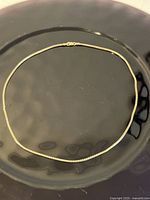 Full view of the 17.75-inch box chain necklace laid in a circle on a dark surface