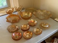 Wide shot of the carnival glass lot showing all pieces arranged on a white surface near window light.
