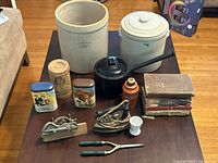 Photo showing the full lot on table with crocks, tins, books, tools and egg cup visible.