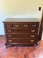 Front view showing the six drawers and brass hardware on the mahogany dresser.