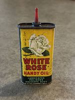 Front view of the vintage Yellow White Rose Handy Oil tin can with white rose logo and red spout, showing lithographed graphics and wear.